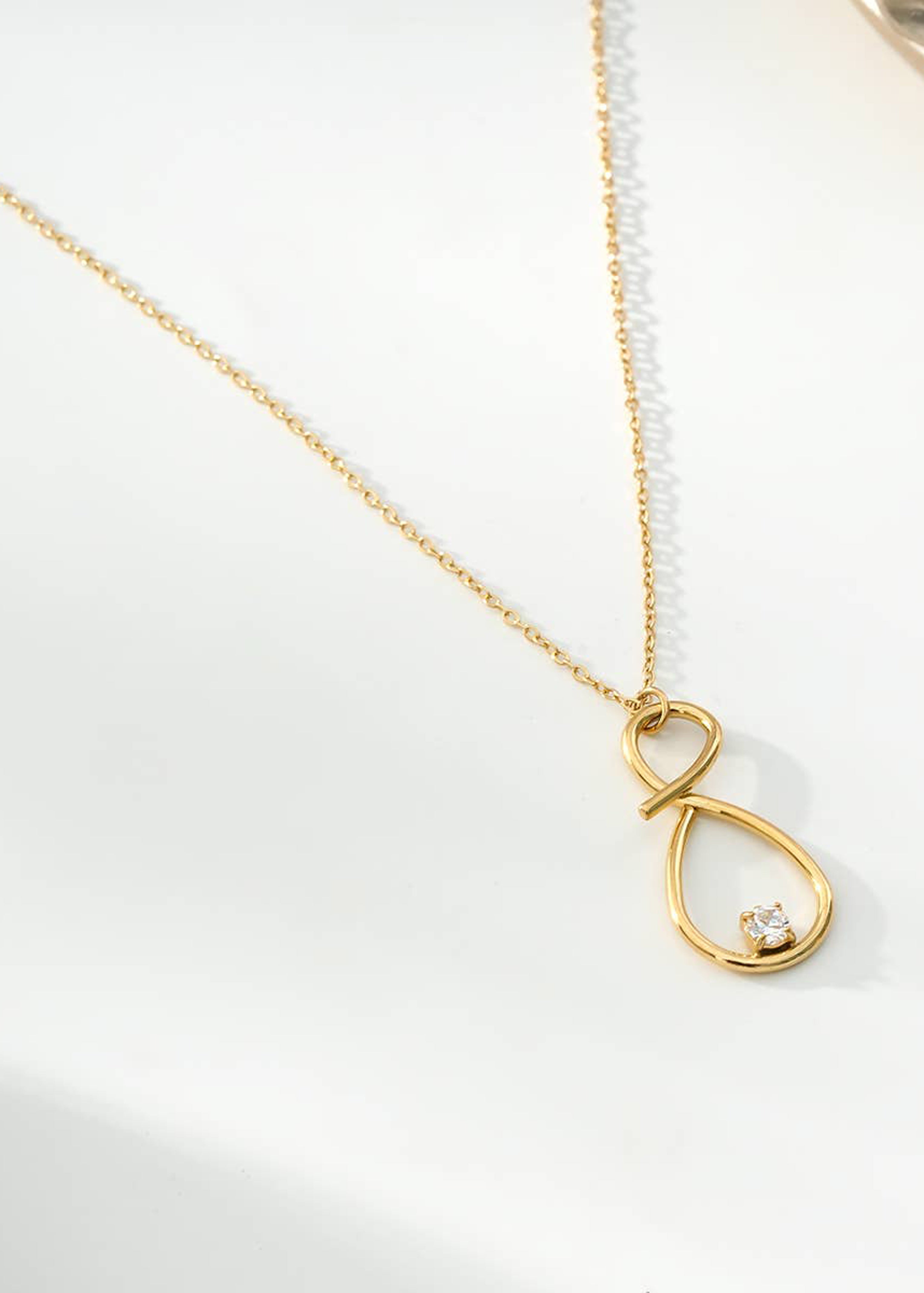 Colar com pingente número oito dourado e strass lineares